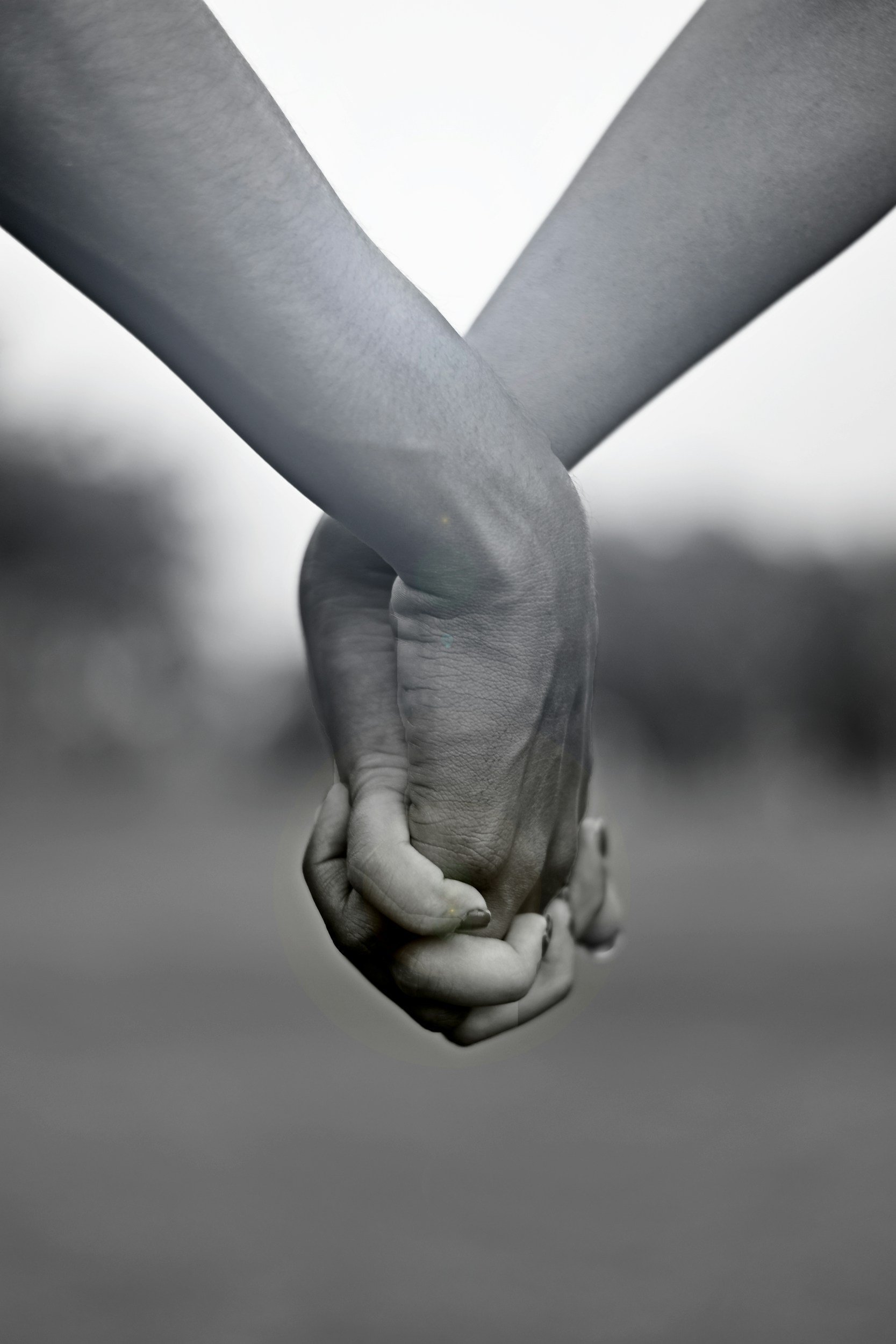 Close-up of two people holding hands, black and white photo.